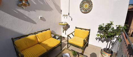 A patio with a sofa, chairs, a table, a potted plant, and decorative wall elements.
