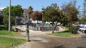 Un parque con un área de juegos, un sendero pavimentado y árboles a su alrededor.