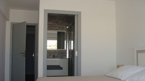 Un dormitorio con una cama, una puerta que da a un baño y vistas al exterior.
