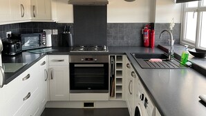 Eine moderne Küche mit weißen Schränken, einem eingebauten Backofen, einem Herd, einer Waschmaschine und einem Spülbecken.