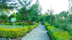 A stone pathway in a park with a sign indicating a fire assembly point. - Naivasha Peppercorn Holiday Resort (Naivasha)