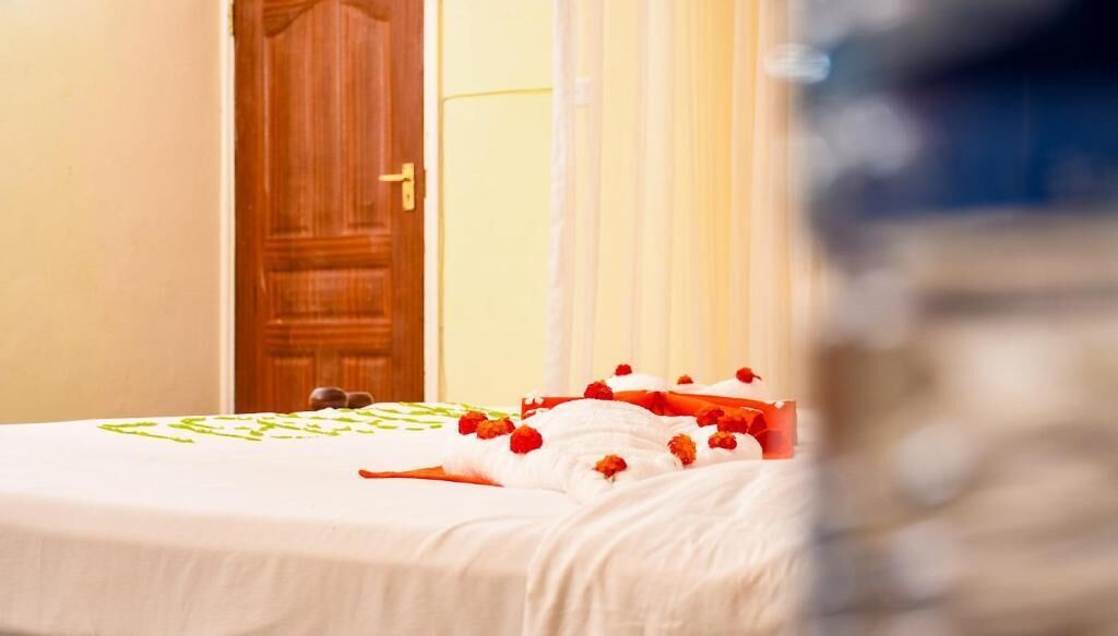 A hotel room with a bed, a wooden door, and a curtain.
