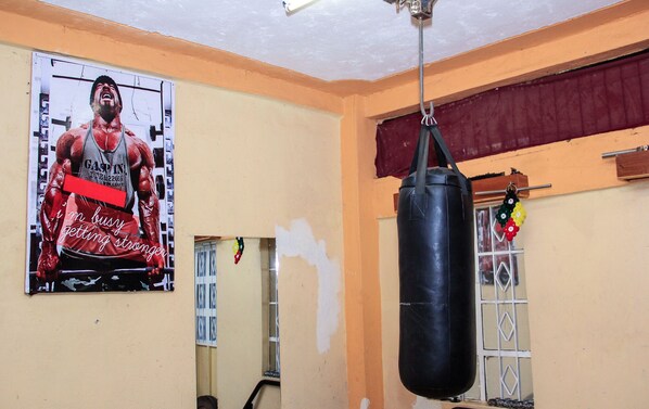 Una habitación con un saco de boxeo, un cartel en la pared y una ventana decorada.