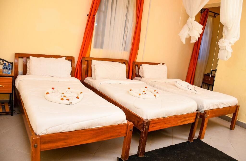A room with two wooden beds, each with white linens and a towel with orange flowers.