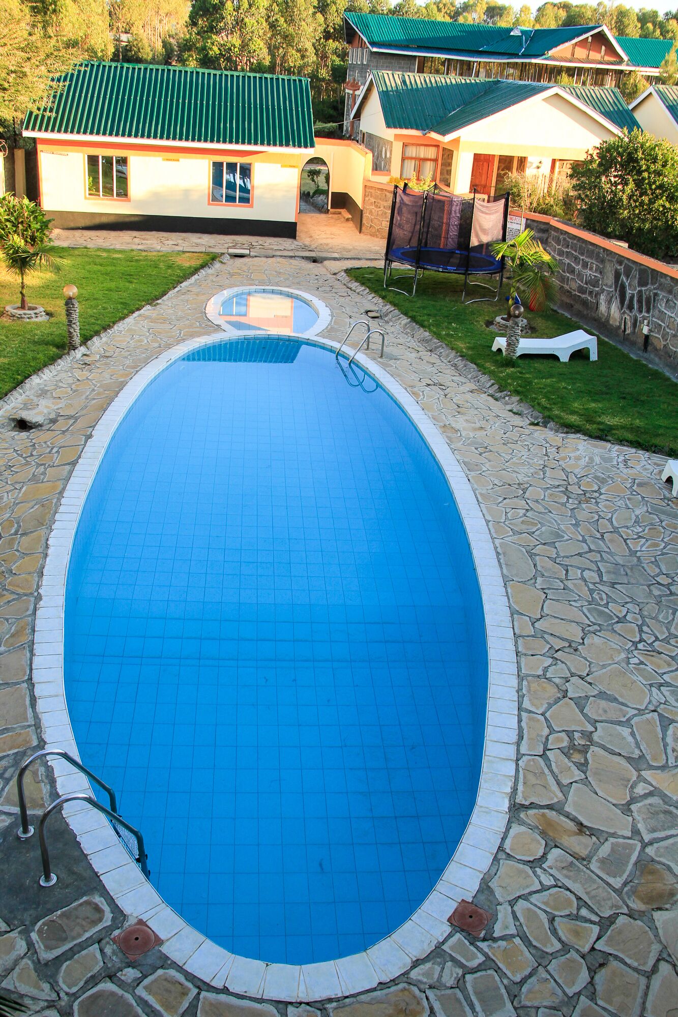 A swimming pool with a stone border, surrounded by a stone patio.
