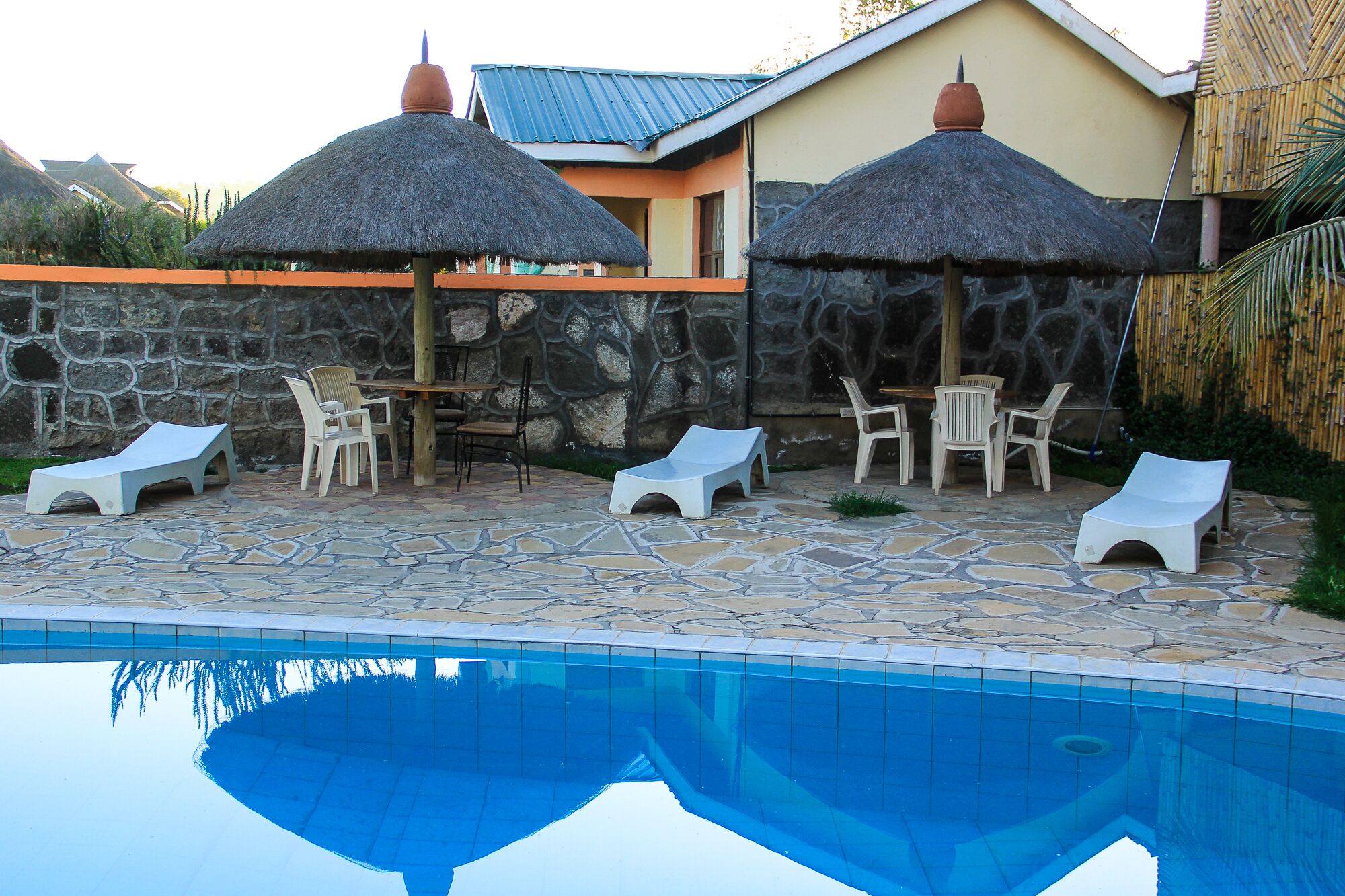 A poolside area with lounge chairs, umbrellas, and a stone patio.