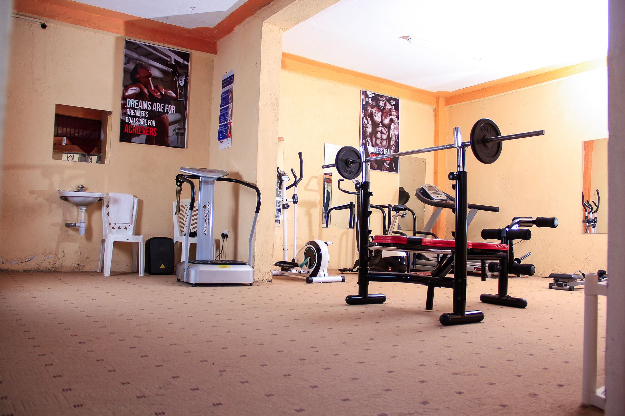 A gym with exercise equipment, a mirror, and motivational posters on the walls.