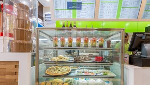 Eine Kühlvitrine mit verschiedenen Speisen, darunter Pizza, Salate und verpackte Waren.