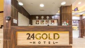 Eine Rezeption im 24 GOLD HOTEL mit Holzdesign, Uhren und einer Flagge.