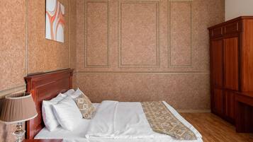 Habitación de hotel con cama de madera, mesita de noche con lámpara, armario y una pared decorada con un cuadro.