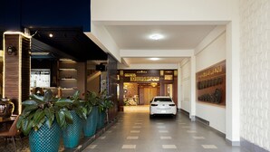 Een hotellobby met een auto in het midden, grote potplanten en een receptiebalie.