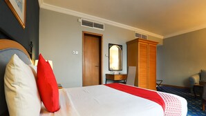 A hotel room with a bed, a wooden wardrobe, a desk, and a chair. - City Plaza Hotel (Al-Fujairah)