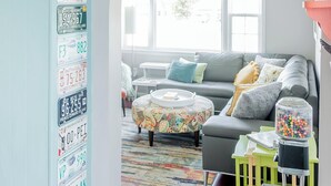 Een woonkamer met een lichtblauwe wand, een bank, een salontafel en een vloerkleed.