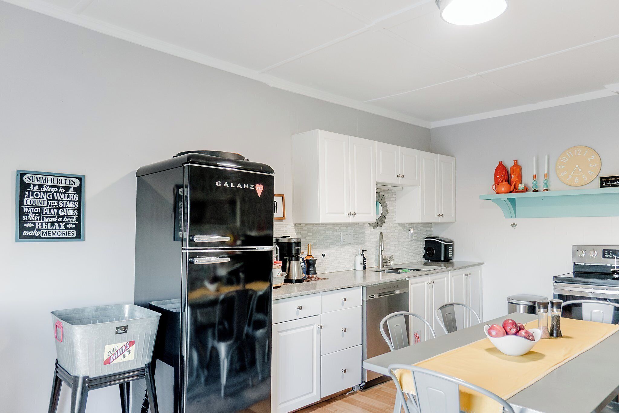 A modern kitchen with white cabinets, a black refrigerator, and a dining area with a table and chairs.