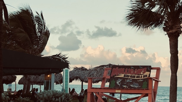 Eine Strandhausbar und ein Grill mit einem Reetdach und einem Schild.