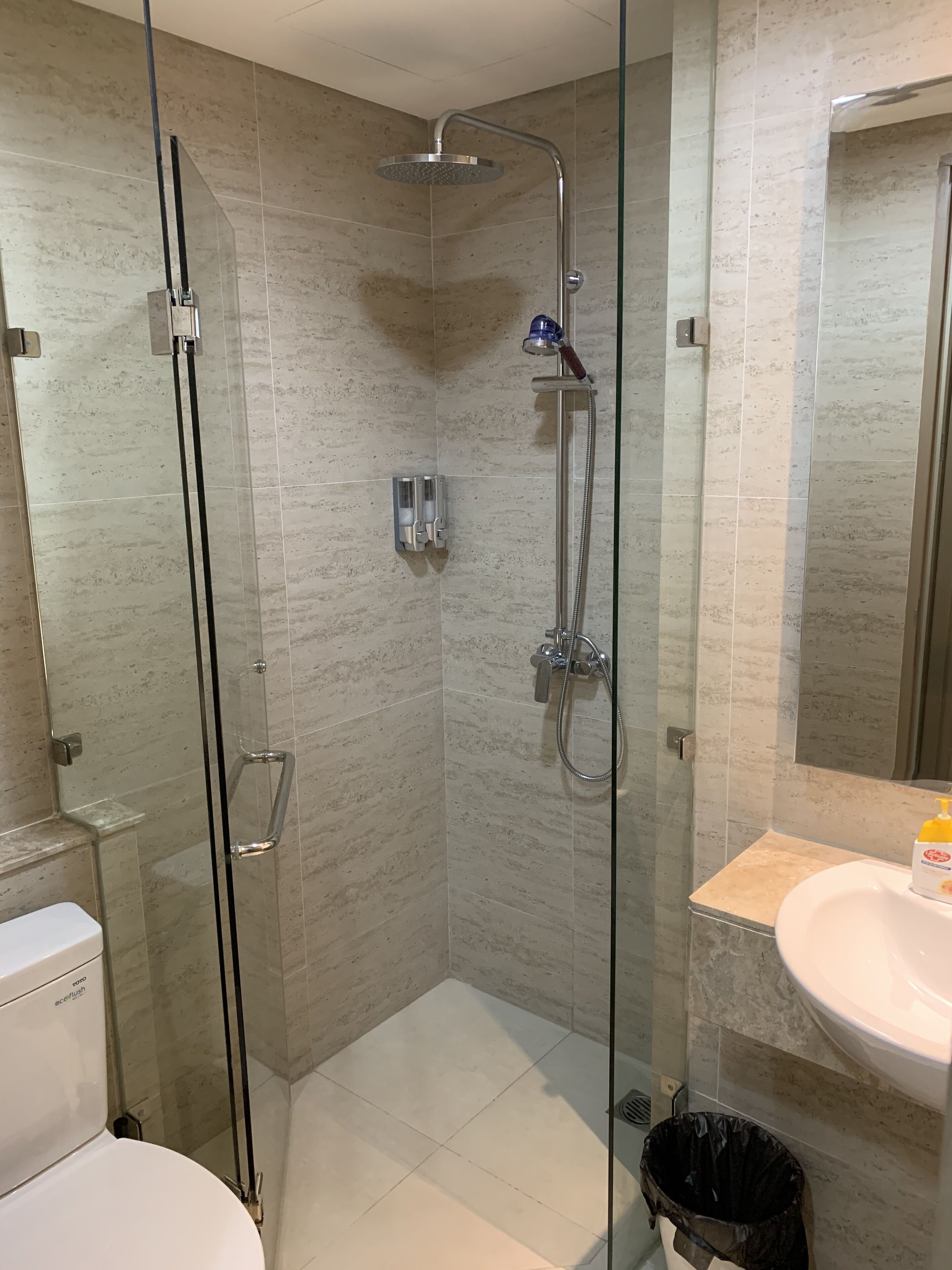 Un bagno moderno con doccia vetro, lavabo bianco e water.