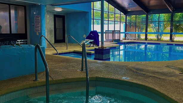 Una piscina interna con acqua cristallina, una postazione di salvataggio e un cartello con le regole della piscina.