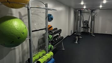 A gym with exercise equipment, including a rack with medicine balls, dumbbells, and resistance bands.