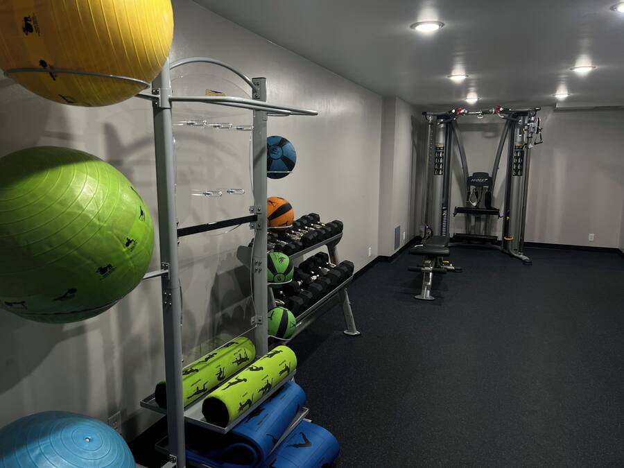 A gym with exercise equipment, including a rack with medicine balls, dumbbells, and resistance bands.