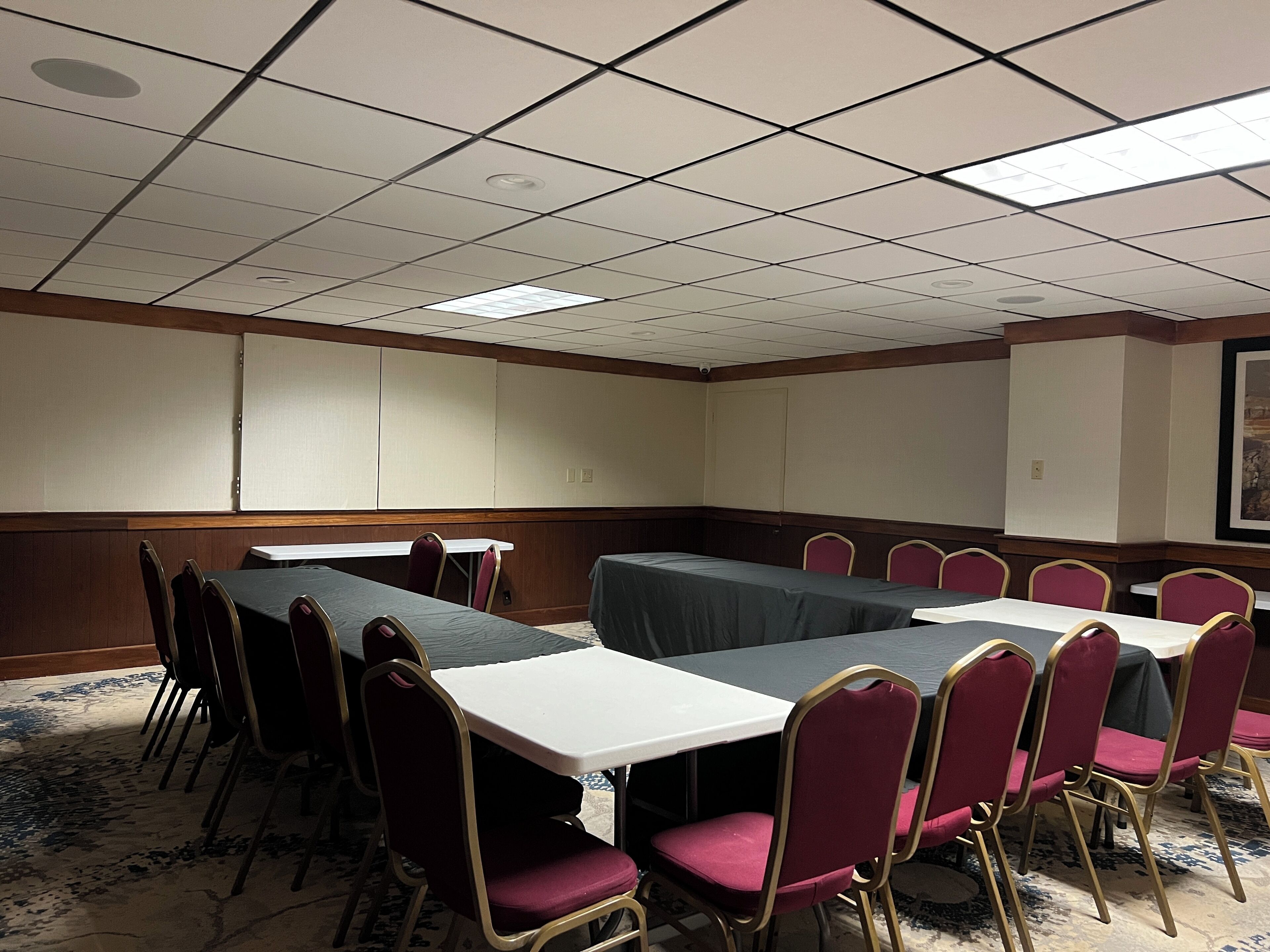 A conference room with a long table, multiple chairs, and a carpeted floor.