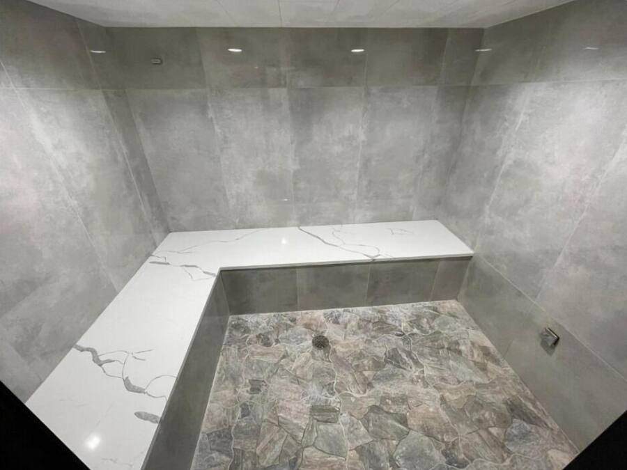 A modern bathroom with a marble vanity, a stone-tiled shower area, and recessed lighting.
