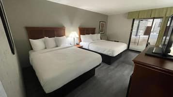 Habitación de hotel con dos camas, un escritorio y una ventana con vistas.