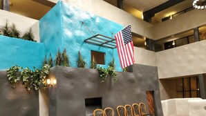 Una hall con parete blu, una bandiera americana, un'area relax con sedute in legno e un piccolo giardino con piante.