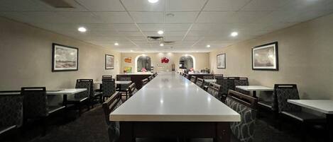 A conference room with a long table and chairs, a patterned carpet, and framed pictures on the walls.
