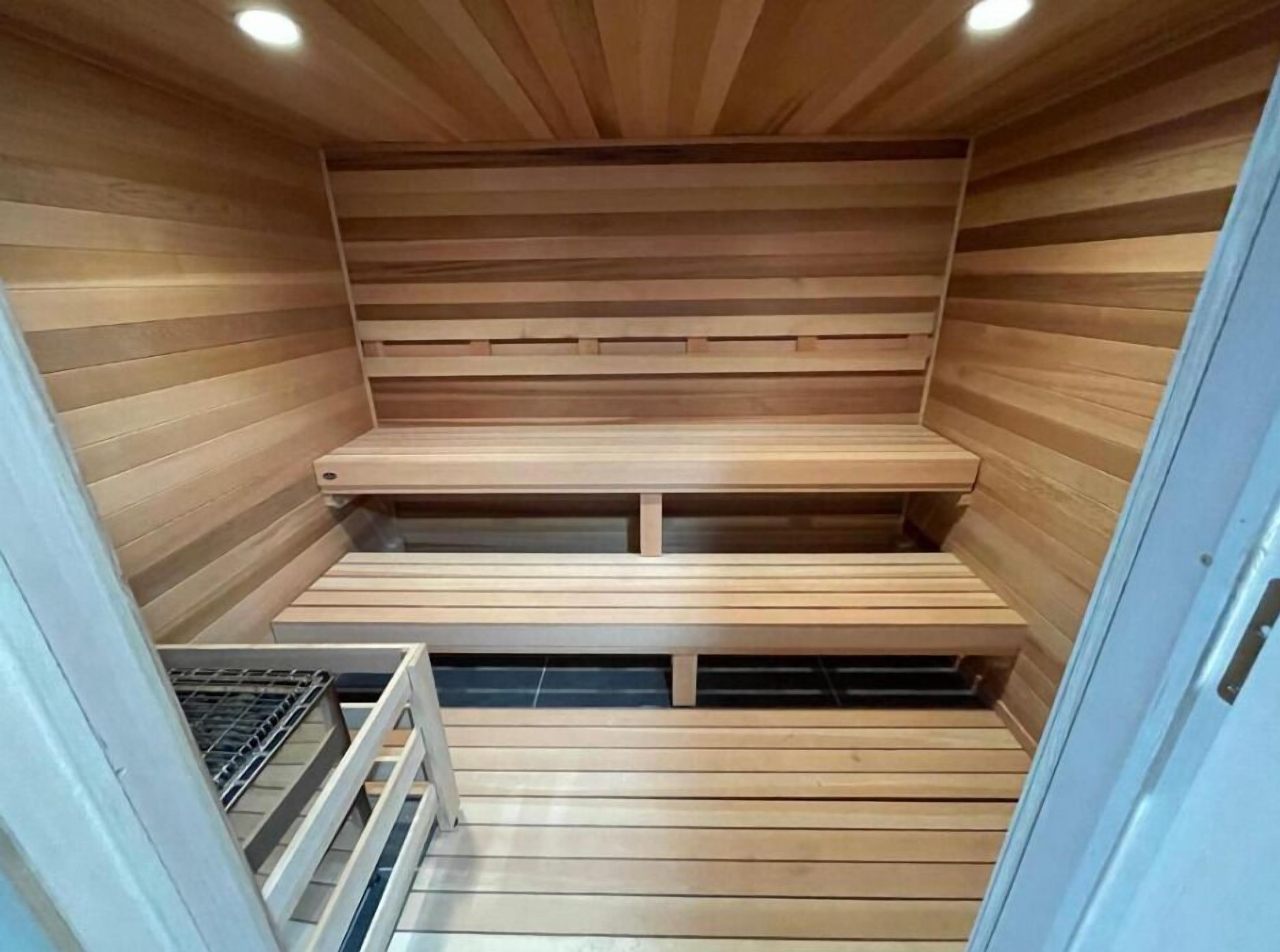 A sauna with wooden benches and a metal railing.