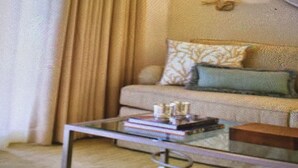 A living room with a sofa, a coffee table, and a wall-mounted light fixture. - Beautifully situated above the Pacific within a tranquil natural sactunctuary. (Carlsbad)