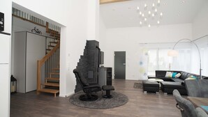 A modern living room with a black leather sofa, a black recliner, and a wooden staircase. - TLA Modern and cozy holiday house freestanding (Waldmohr)