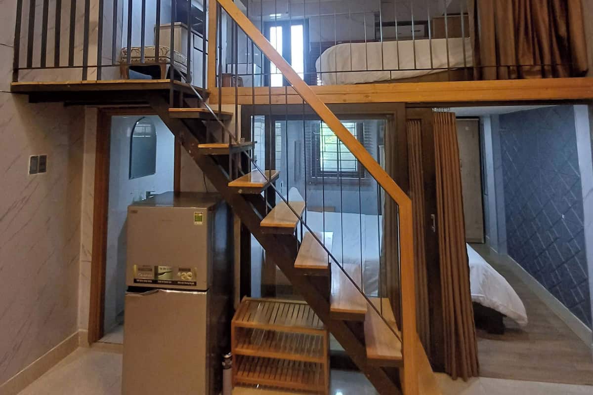 A modern interior with a wooden staircase, a ceiling light fixture, and a bed.