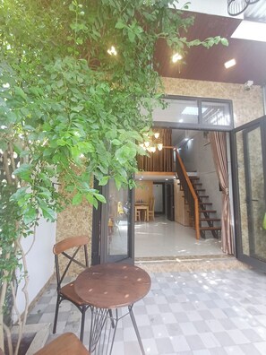 A dining area with a table and chairs, a staircase, and a glass door leading to another room. - Seashine Apartment (Da Nang)