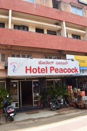 A building with a sign reading "Hotel Peacock" and a sign for "Jacadish Automobiles" in the background. - Hotel Peacock (Hubli)