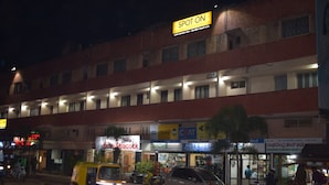 Un hotel de varios pisos, con un cartel que dice 'Spot On' en la parte superior y diversas tiendas en la planta baja.