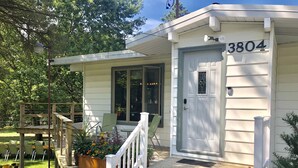 Ein Haus mit der Nummer 3804 an der Tür, einer Veranda mit einer hölzernen Bank und einem kleinen Garten.