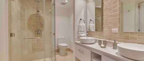 A modern bathroom with a glass shower enclosure, a toilet, and a double sink vanity with a large mirror.