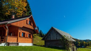 Une cabane en bois avec un toit en pente, une véranda et une petite fenêtre.