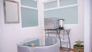 A compact kitchen with a round glass table, a built-in stove, and a potted plant.