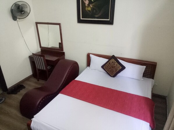 A hotel room with a bed, a desk, a chair, and a fan. - Mua Xuan Hotel (Hanoi)