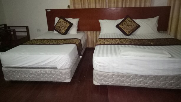 Twee enkele bedden met houten hoofdborden, wit beddengoed en decoratieve kussens.