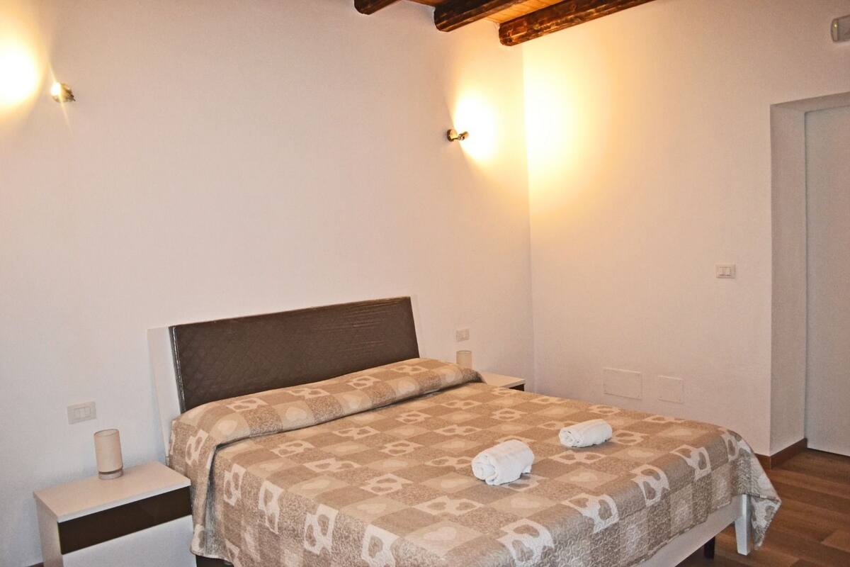 Un dormitorio con cama, lámparas de noche y una viga de madera en el techo.