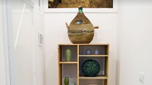 A corner with a wooden shelf holding various decorative items, a door, and a wall-mounted artwork. - Dimora Castelli (Palermo)