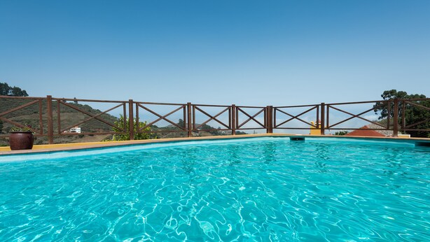 Una piscina azul cristalina con un muelle de madera y una barandilla de metal.