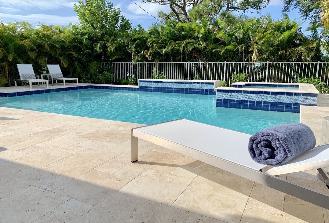 A swimming pool with two lounge chairs and a towel.