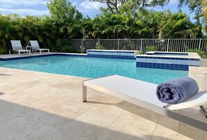 A swimming pool with two lounge chairs and a towel.