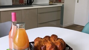 A kitchen with a white countertop, a coffee maker, and a basket of bread on a table.