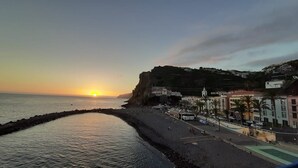 Eine Küstenlandschaft mit Sonnenuntergang, einer Promenade und Gebäuden am Ufer.