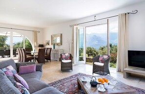 Un salón amplio con sofá, sillas, una mesa de centro y televisor.