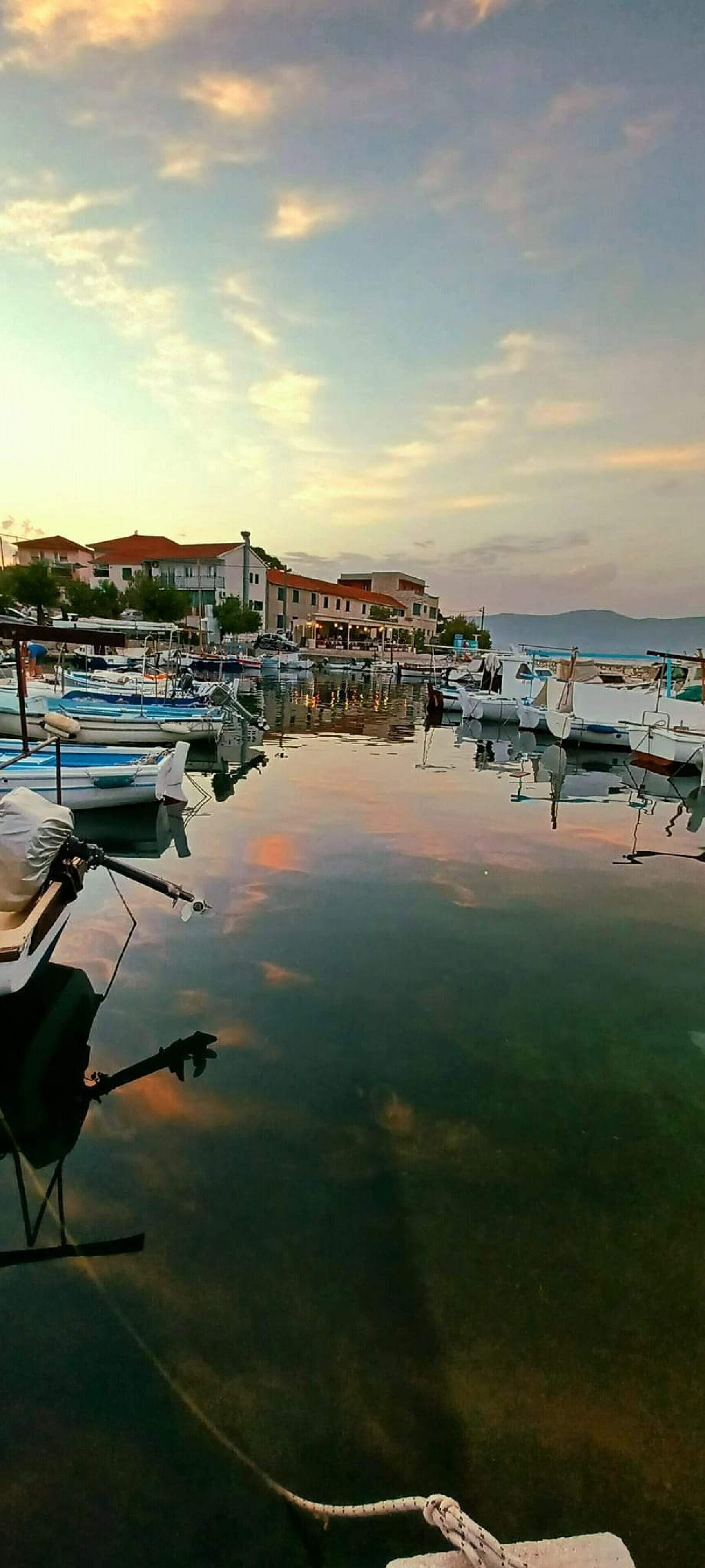 A marina with boats docked, a clear sky, and buildings in the background.